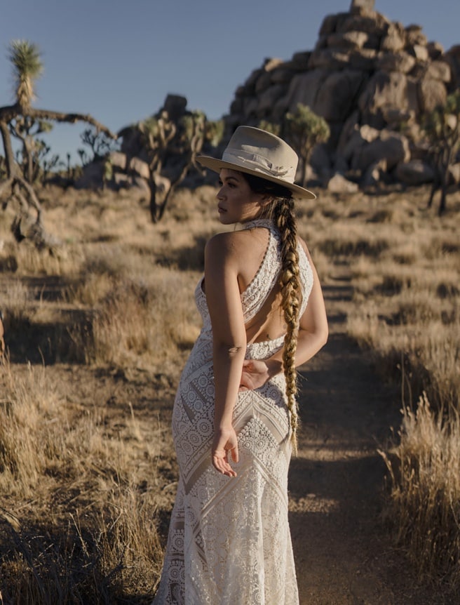 Bride in bohemian wedding dress with hat at her desert wedding in Joshua Tree National Park.
