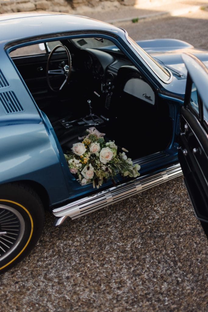 A wedding bouquet in the seat of a vintage corvette ar an elopement ceremony.