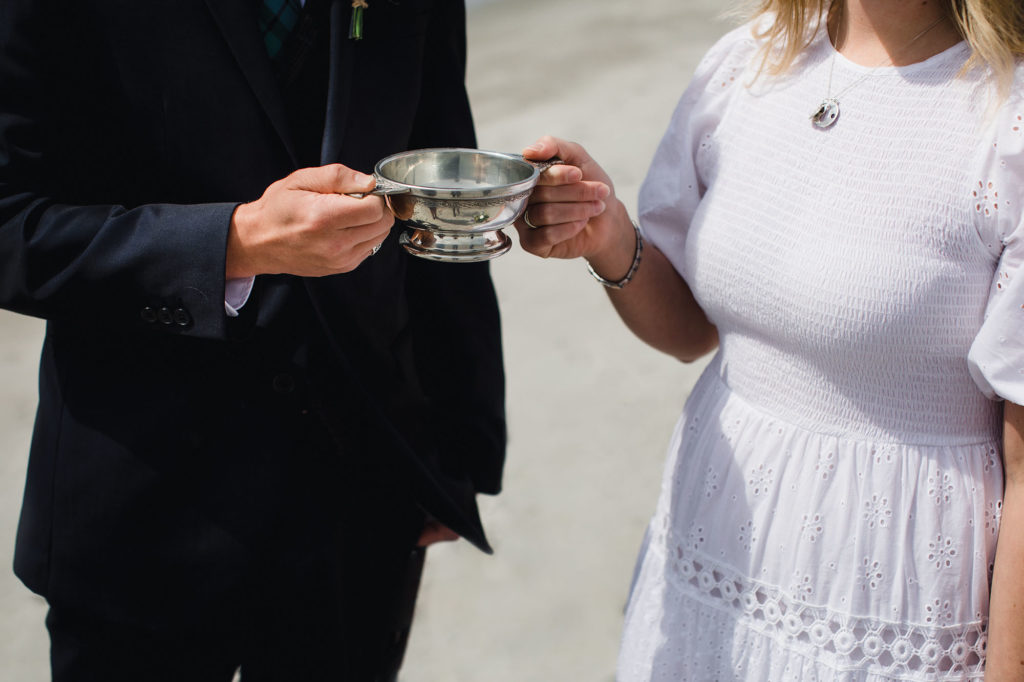 A bride and groom share their wedding day quaich cup.